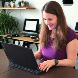 Szilvia from Decoding Denmark working on a laptop to support internationals with CV, LinkedIn, and career clarity in Denmark.